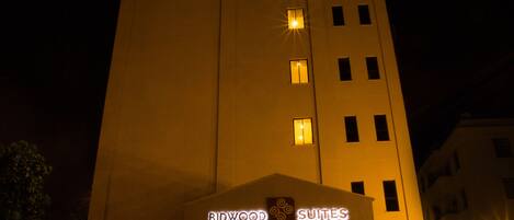 Un edificio de gran altura con ventanas iluminadas y un letrero que dice "Bidwood Suites".