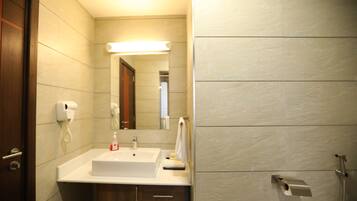 Un baño con lavamanos blanco, espejo, toallero y ducha.