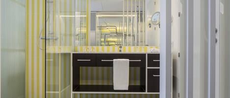 A modern bathroom with a glass shower enclosure, a vanity with a towel rack, and a mirror.