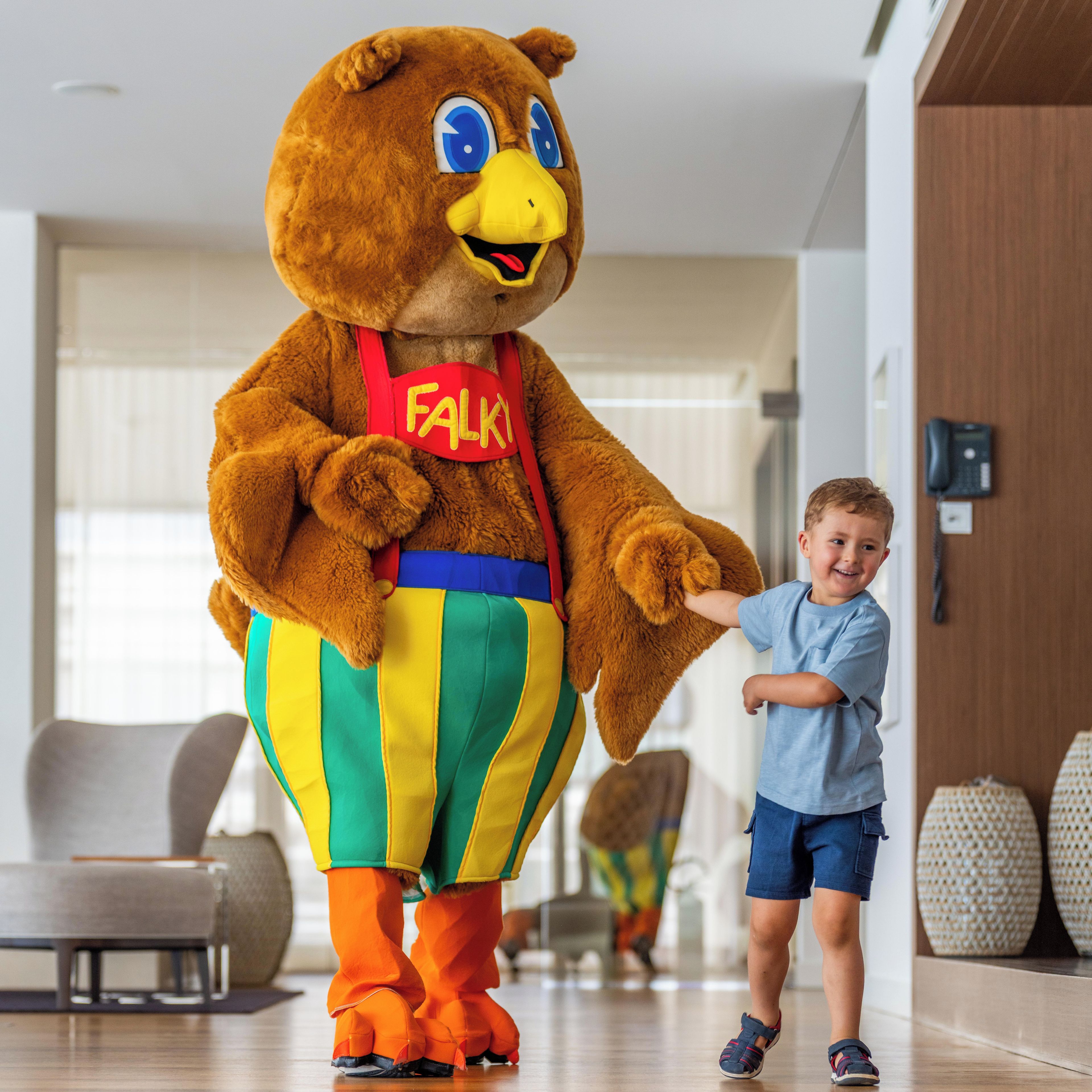 A mascot in a colorful costume standing in a room with a child.