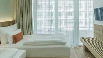 A hotel room with a bed, a bench, and a TV.