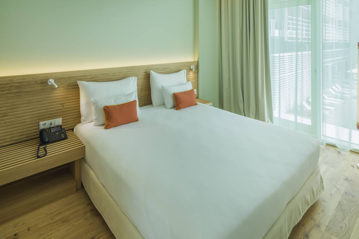 A hotel room with a large bed, wooden headboard, and a bedside phone.
