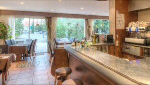 Een bar met een toonbank, krukken en uitzicht op buiten.