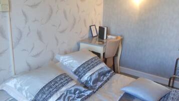 A hotel room with a bed, a desk, and a wall-mounted light.