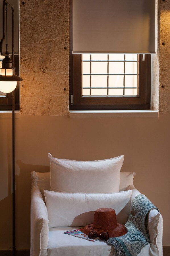 Une pièce confortable avec un lit simple, une fenêtre avec des barreaux, une lampe et un chapeau posé sur le lit.