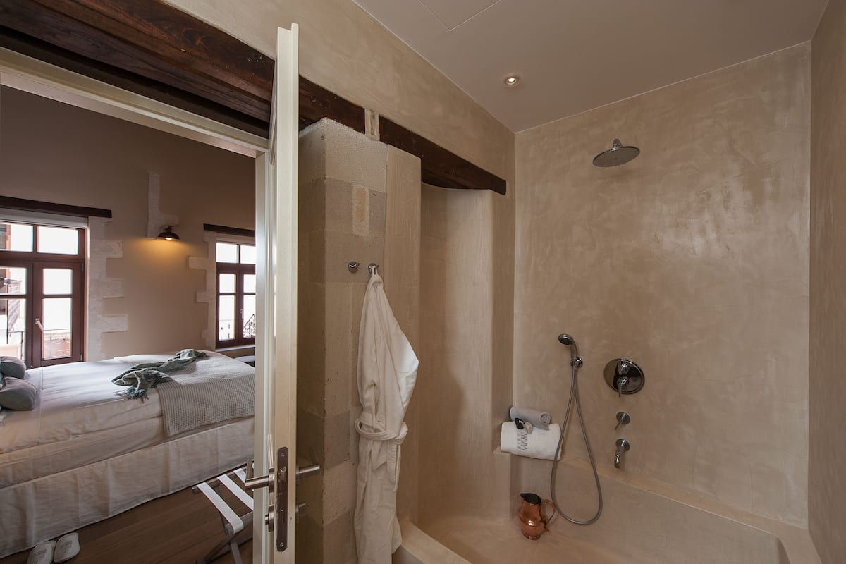 Une salle de bain avec une douche, un porte-serviettes et un lit avec une couverture et un oreiller.