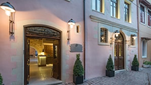 Ein Hotel mit einer steinernen Fassade, gewölbten Eingängen und Blumentöpfen.