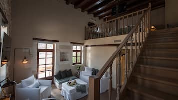 A spacious living area with a wooden staircase, a sofa set, and a dining table.