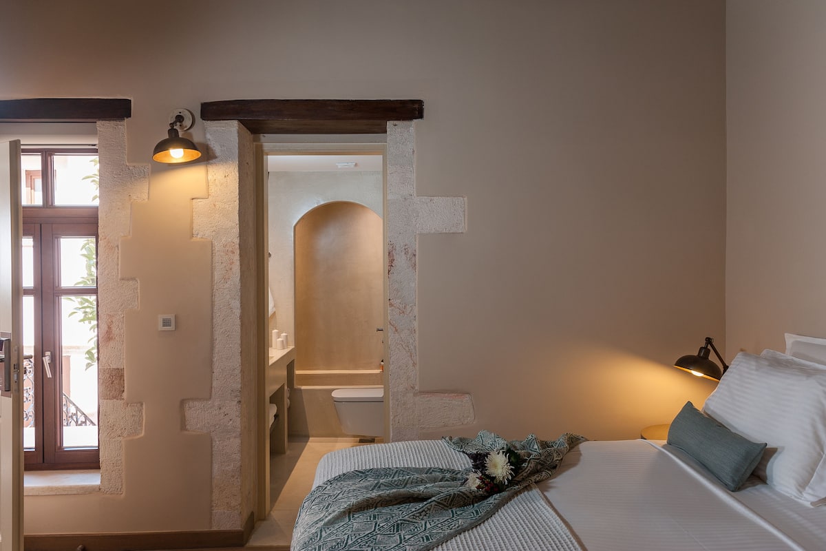 Une chambre à coucher avec un lit, une lampe de chevet et une vue sur la salle de bain.