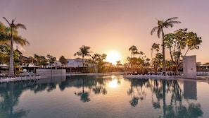 A resort pool with clear water reflecting the sunset, surrounded by palm trees and lounge chairs. - LABRANDA Alyssa Suite Hotel (Yaiza)
