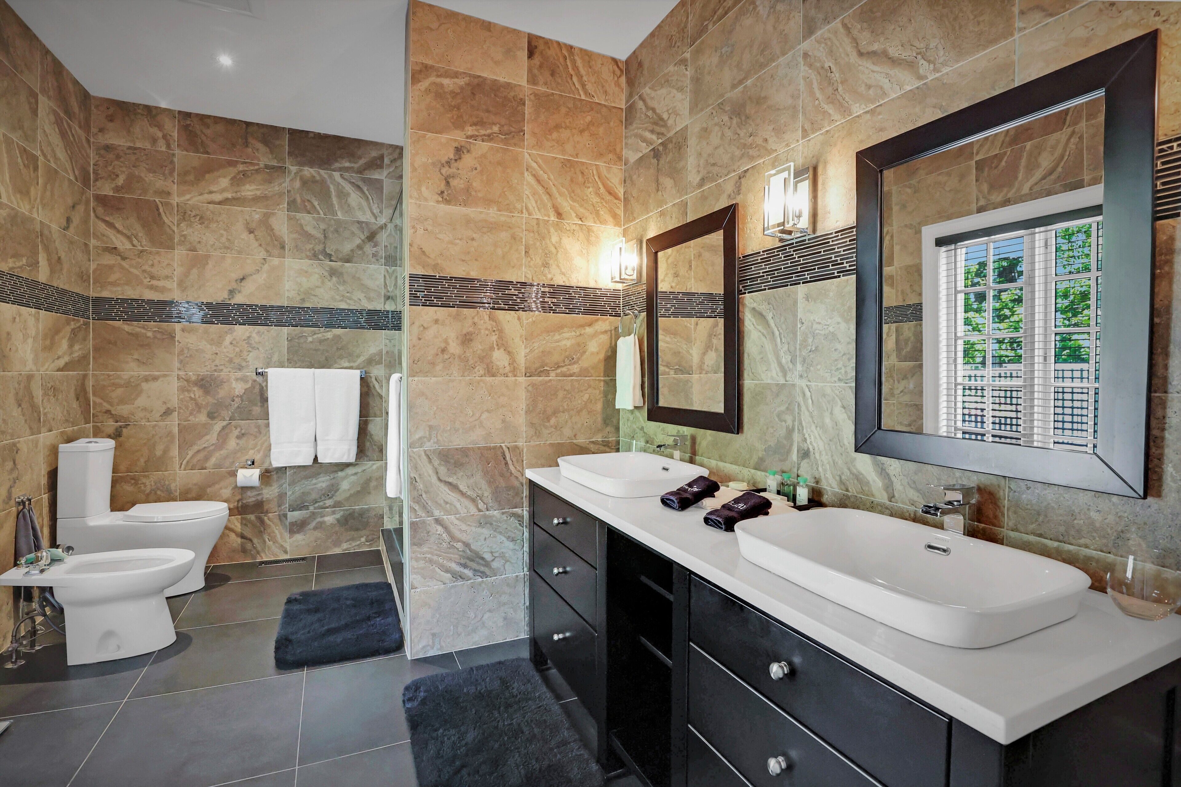 A modern bathroom with two sinks, a toilet, and a shower area.