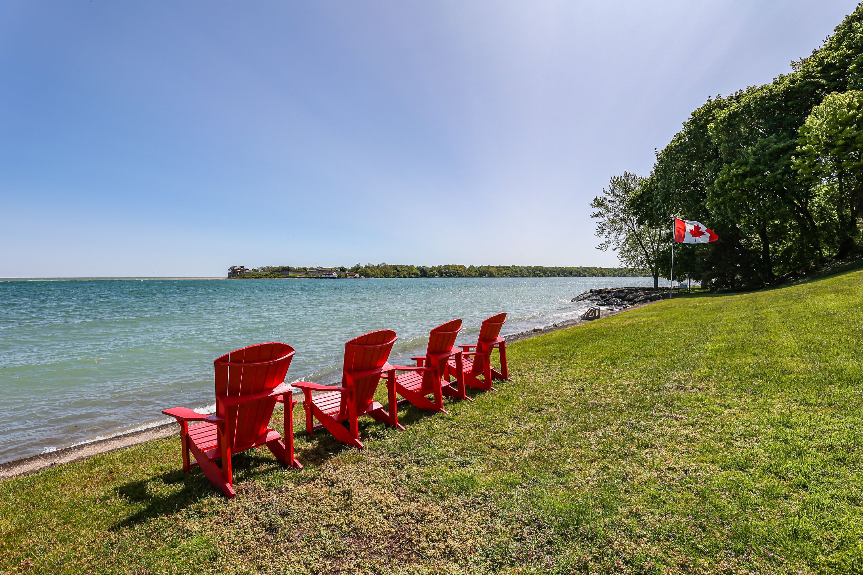 Vista del lago con sillones Adirondack rojos e izada la bandera canadiense.