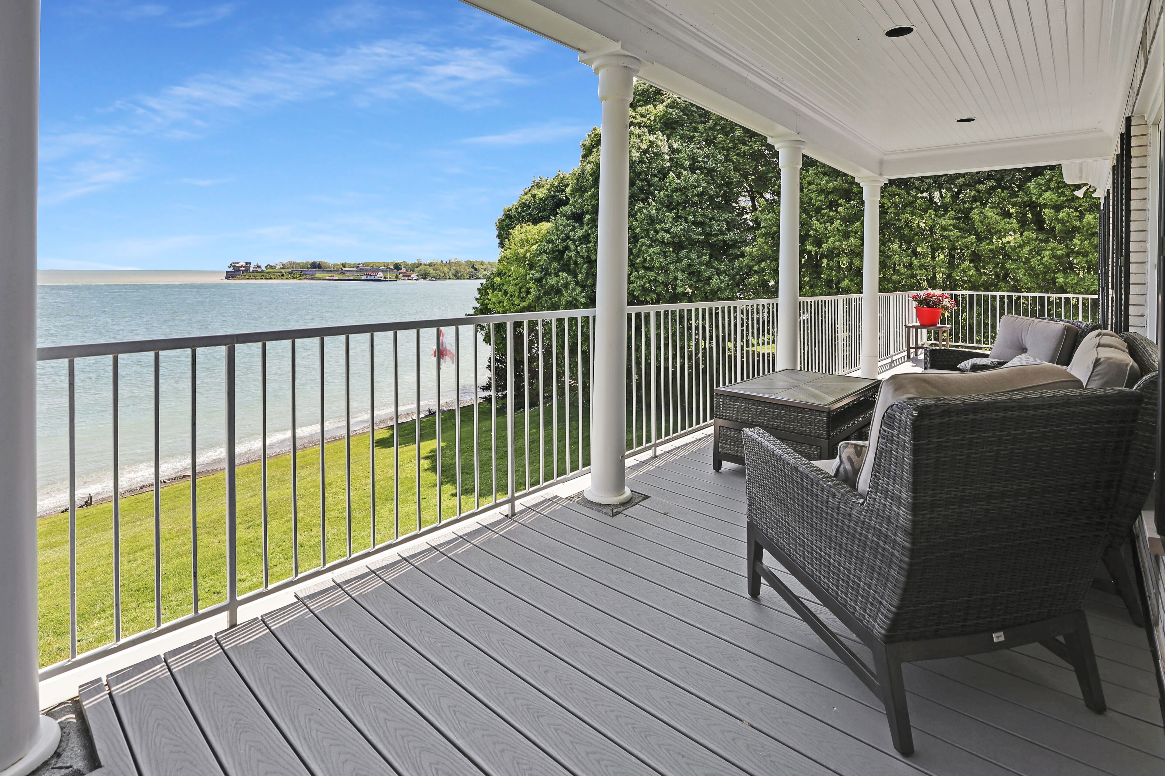 A covered porch with a view of the lake, a wicker sofa, and a small table.