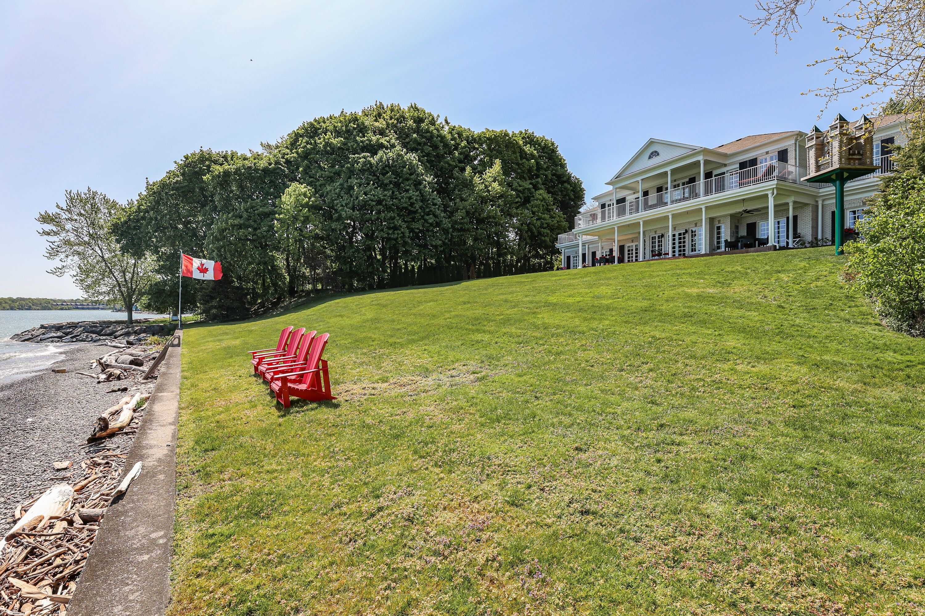 A coastal property with a grassy lawn, red chairs, and a flag.