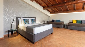 Une chambre à coucher avec un lit, deux canapés, une lampe et un mur décoré d’un motif.