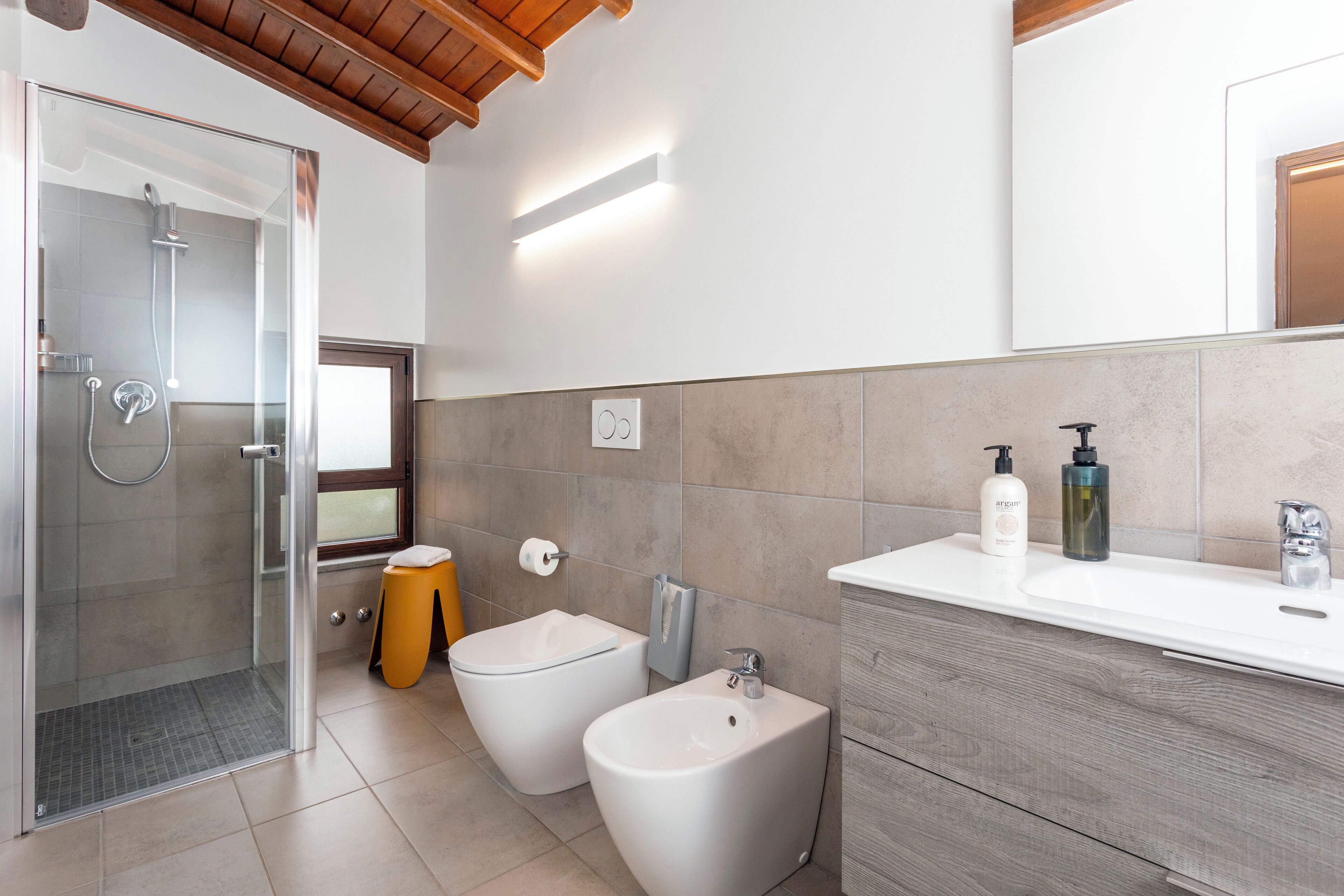 A modern bathroom with a shower, bidets, a vanity with a mirror, and a toilet.