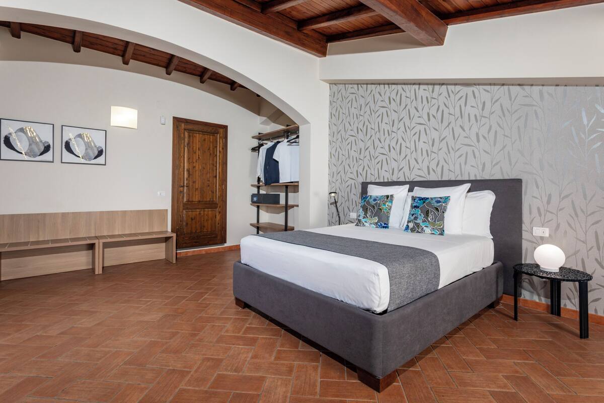 Ein Schlafzimmer mit einem Bett, einer Bank, einem Kleiderschrank und einer Wand mit Muster.