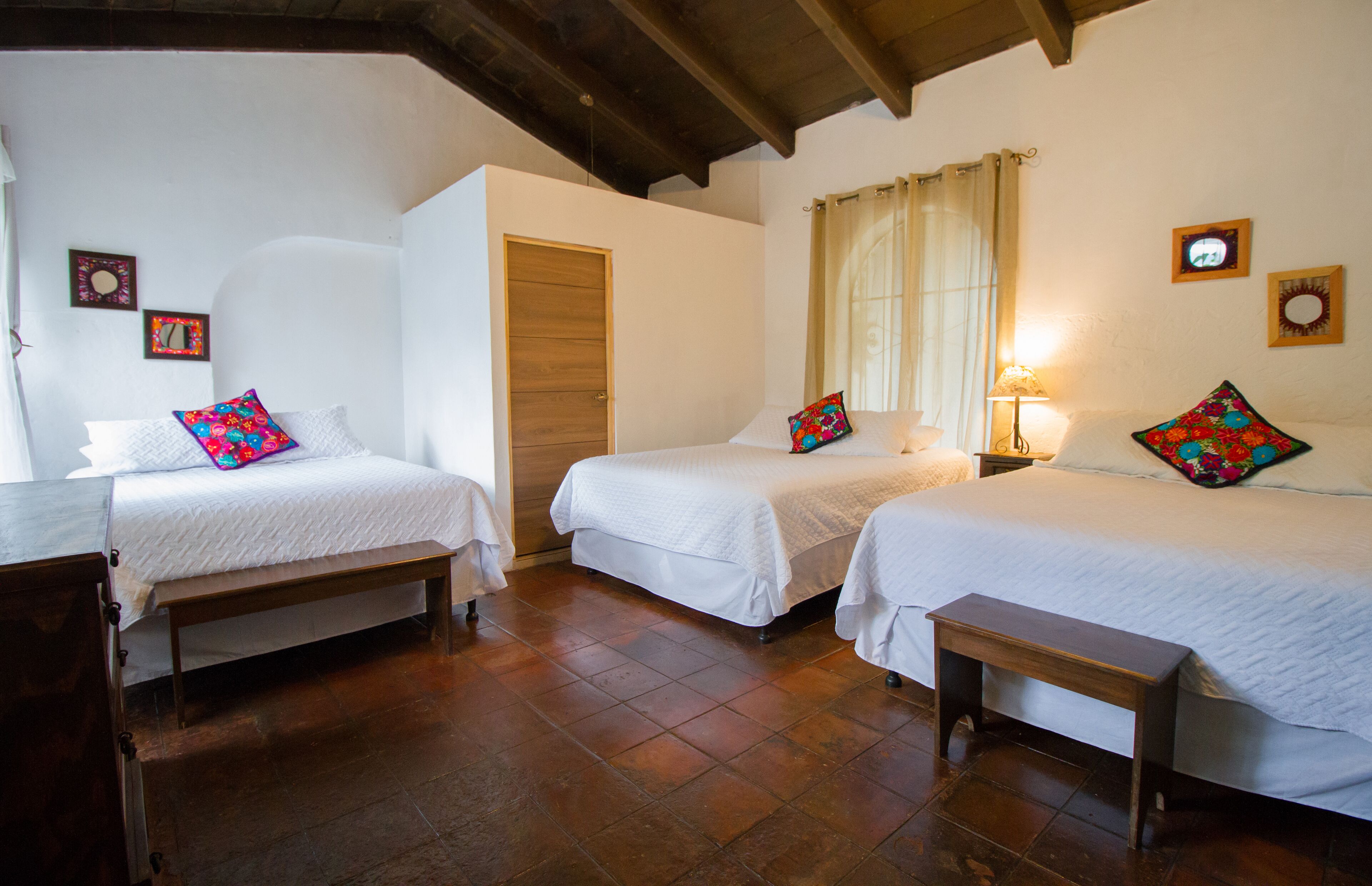 Una habitación con dos camas, un banco de madera y una puerta.
