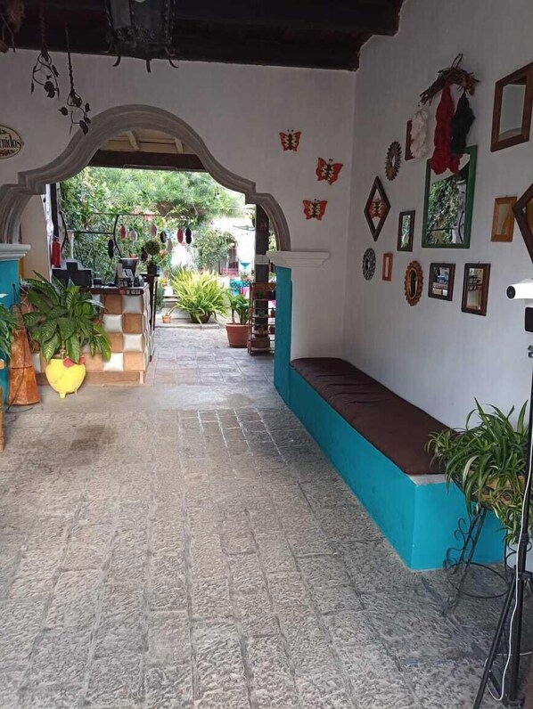 Un interior acogedor con piso a cuadros, un banco azul y diversas plantas en macetas.