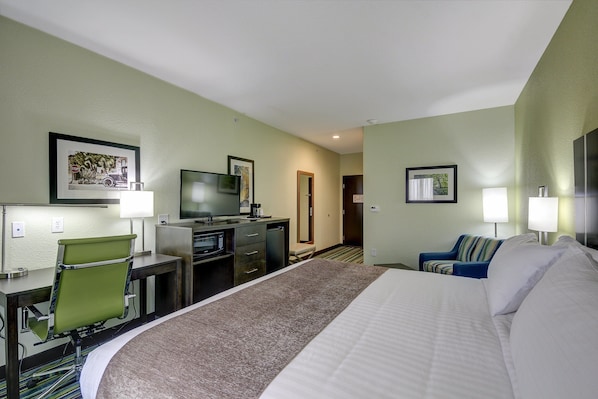 A hotel room with a large bed, a desk with a chair, a television, and a door leading to another room. - Holiday Inn Express & Suites Carrizo Springs by IHG (Carrizo Springs)