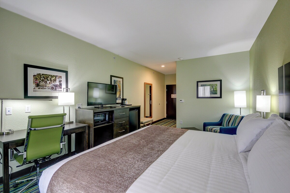Une chambre d’hôtel comprenant un lit, un bureau, une chaise, une télévision et une porte donnant sur une autre pièce.