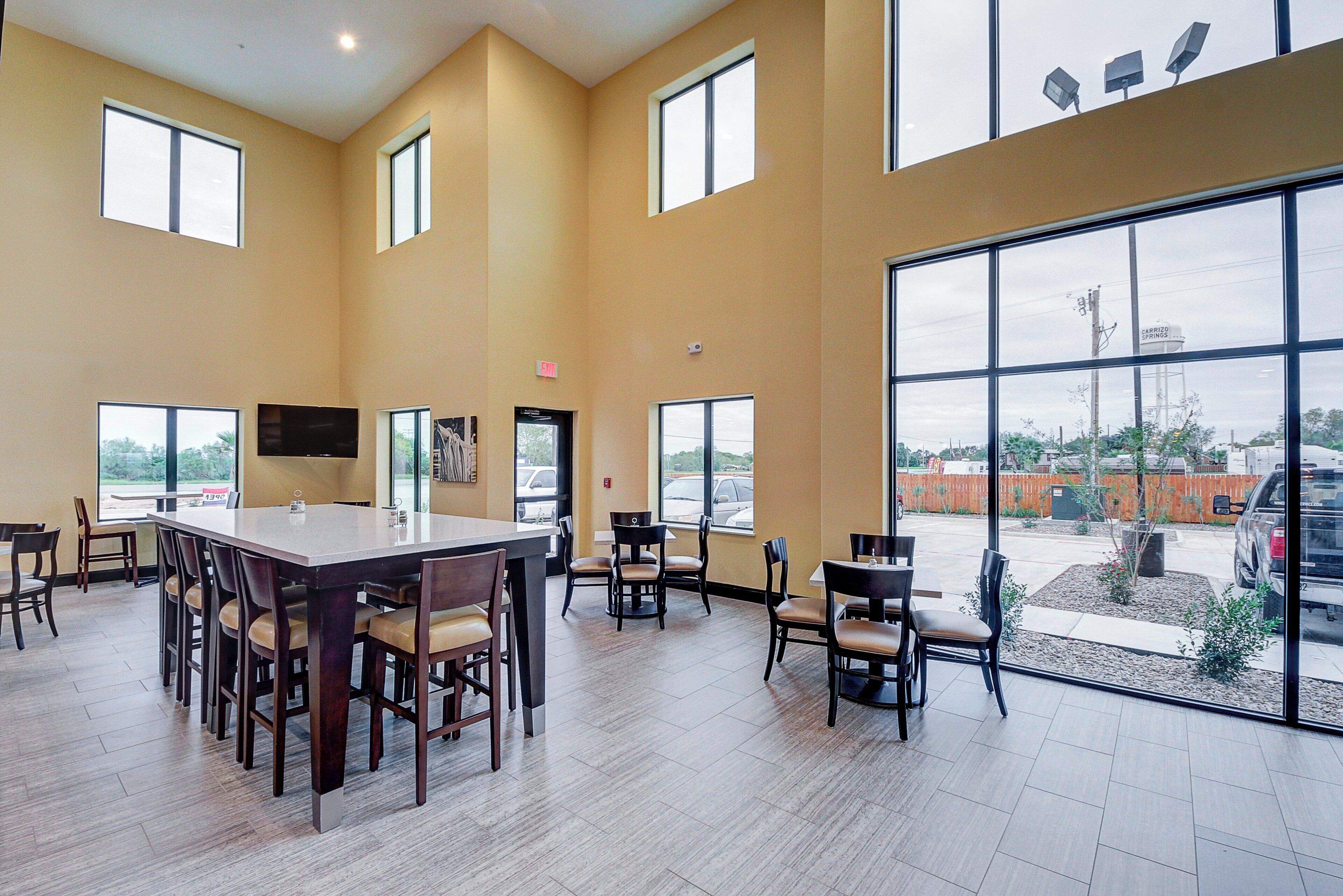 A spacious indoor area with large windows, a central table, and multiple chairs.