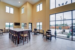 A spacious indoor area with large windows, a central table, and multiple chairs. - Holiday Inn Express & Suites Carrizo Springs by IHG (Carrizo Springs)