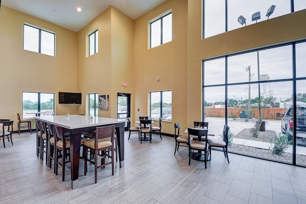 A spacious indoor area with large windows, a central table, and multiple chairs. - Holiday Inn Express & Suites Carrizo Springs by IHG (Carrizo Springs)