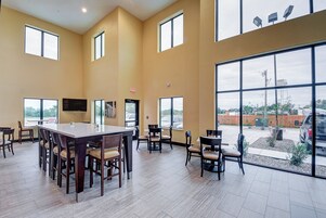 Un espacio interior amplio con ventanas grandes, una mesa central y varias sillas.