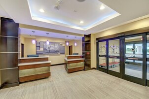 A hotel reception area with a modern design, including a reception desk, pendant lighting, and a glass door entrance.