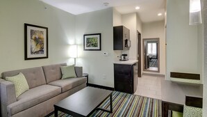 A compact living space with a sofa, coffee table, kitchenette, and a view into the dining area.