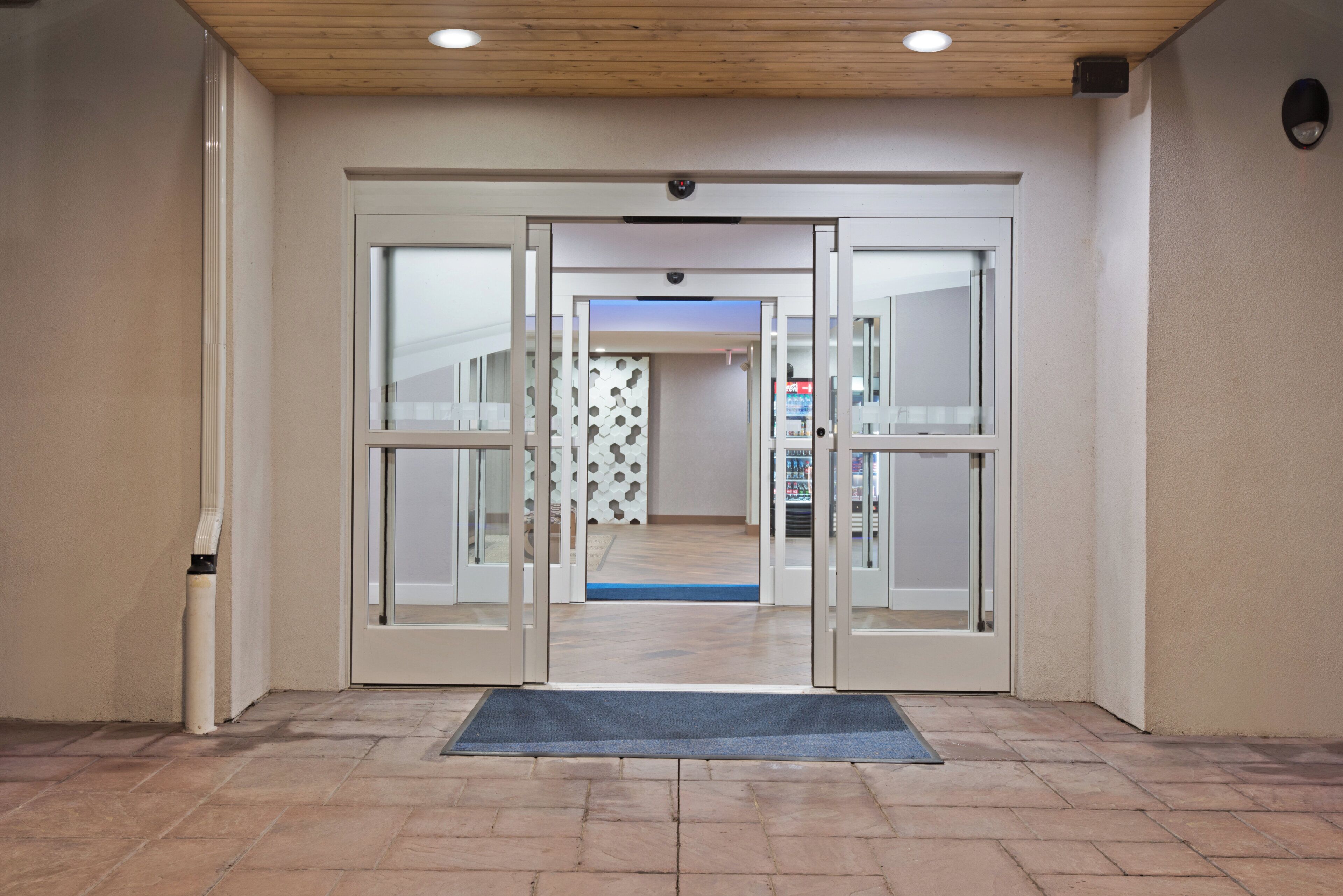 A hotel entrance with a revolving door, a doormat, and a tiled floor.