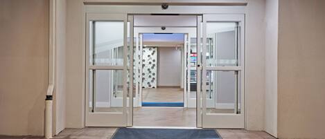 A hotel entrance with a revolving door, a doormat, and a tiled floor.