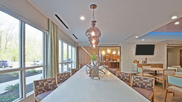 A modern conference room with a long table, comfortable seating, and large windows offering a view of the street. - Holiday Inn Express & Suites New Cumberland by IHG (New Cumberland)