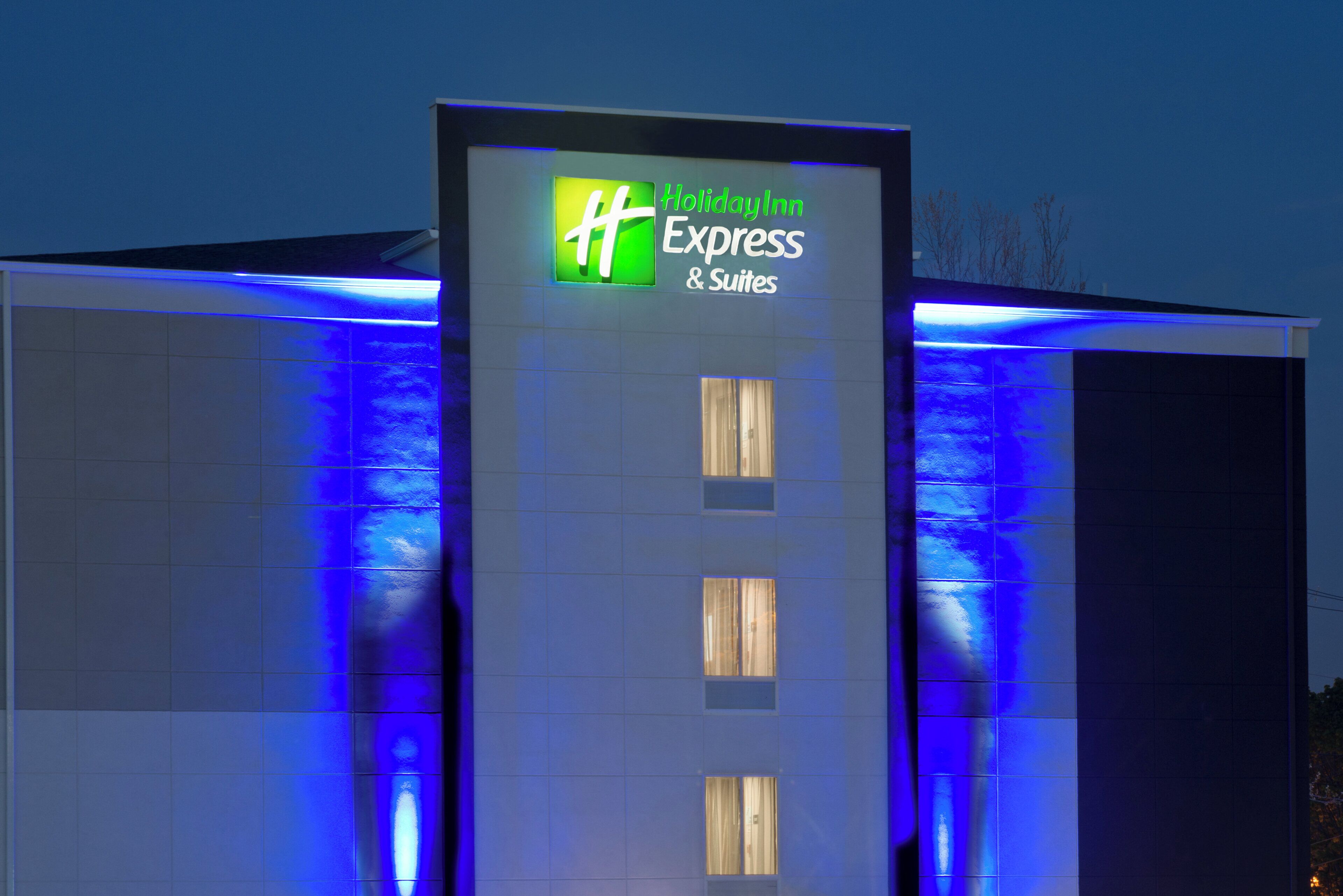 A Holiday Inn Express & Suites building facade with illuminated signage.