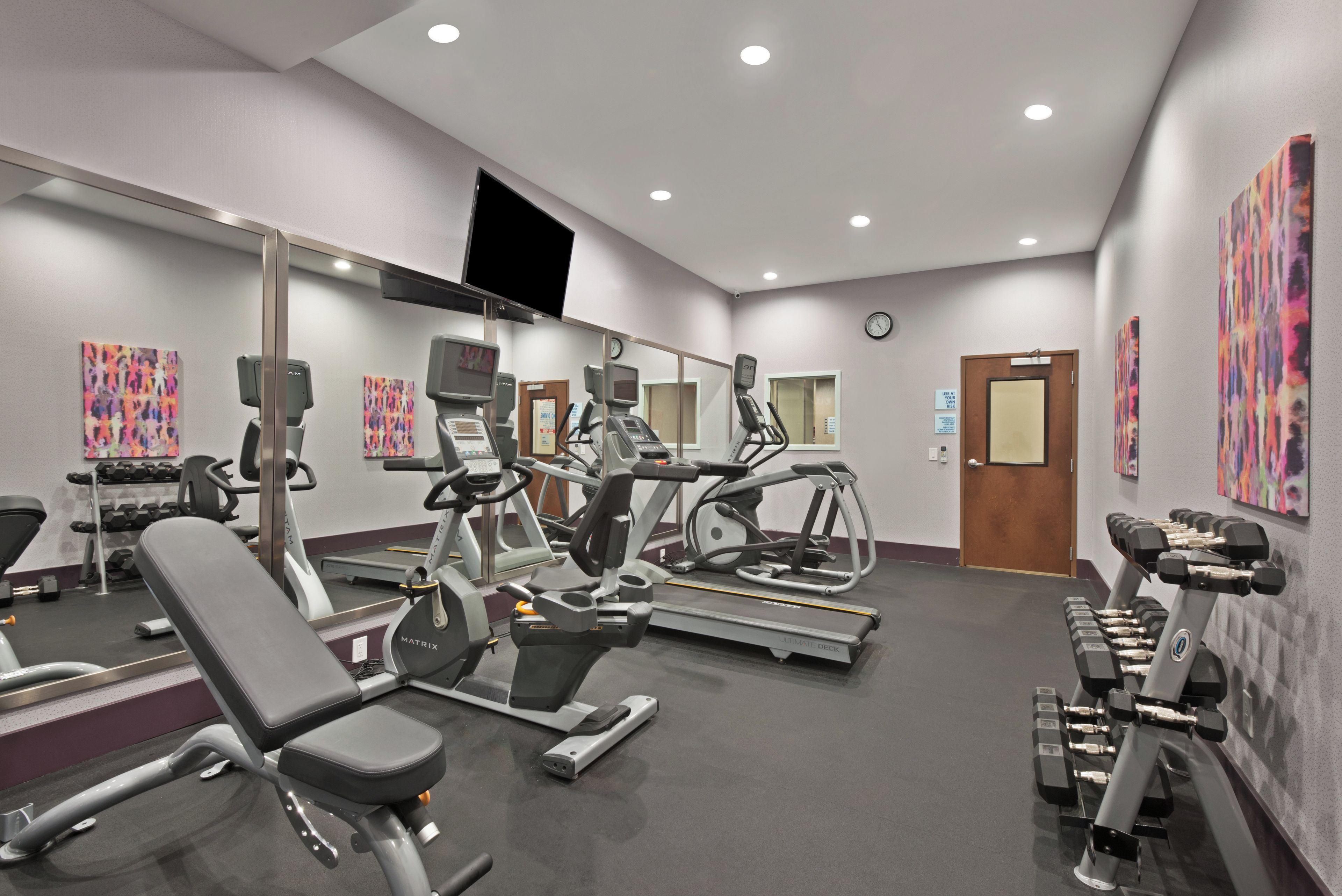A gym with various exercise equipment, including treadmills, stationary bikes, and weight machines.
