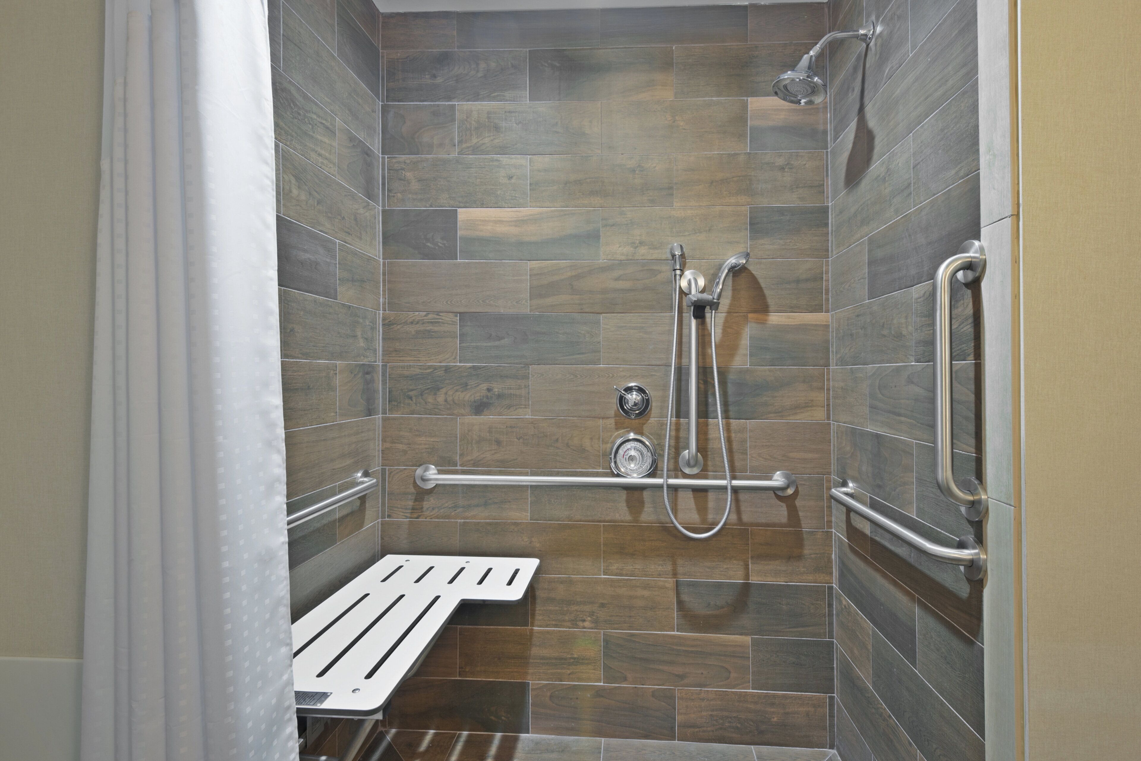 A shower with a handheld showerhead and a handheld faucet.
