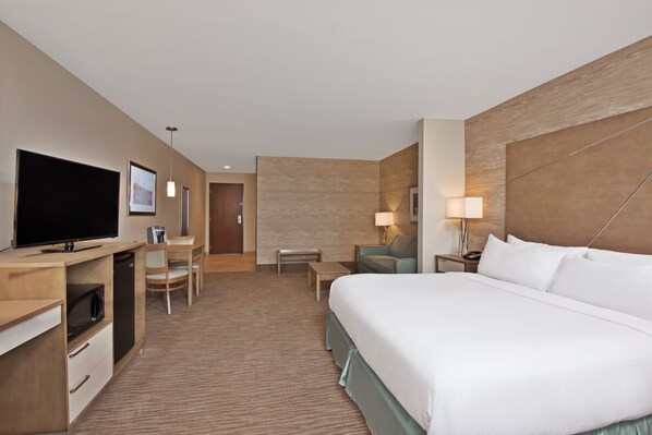 A hotel room with a large bed, a desk with a television, a chair, a small table, and a lamp. - Holiday Inn Express & Suites New Cumberland by IHG (New Cumberland)