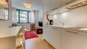 A modern kitchen with white cabinets, a countertop, and a red rug. - LSA Liberdade by Numa (Lisbon)