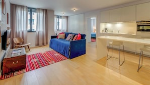 A modern living room with a sofa, a small table, a red patterned rug, and a wooden floor. - LSA Liberdade by Numa (Lisbon)