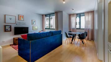 Una sala de estar moderna con un sofá azul, un televisor de pantalla plana y un comedor con mesa y sillas.