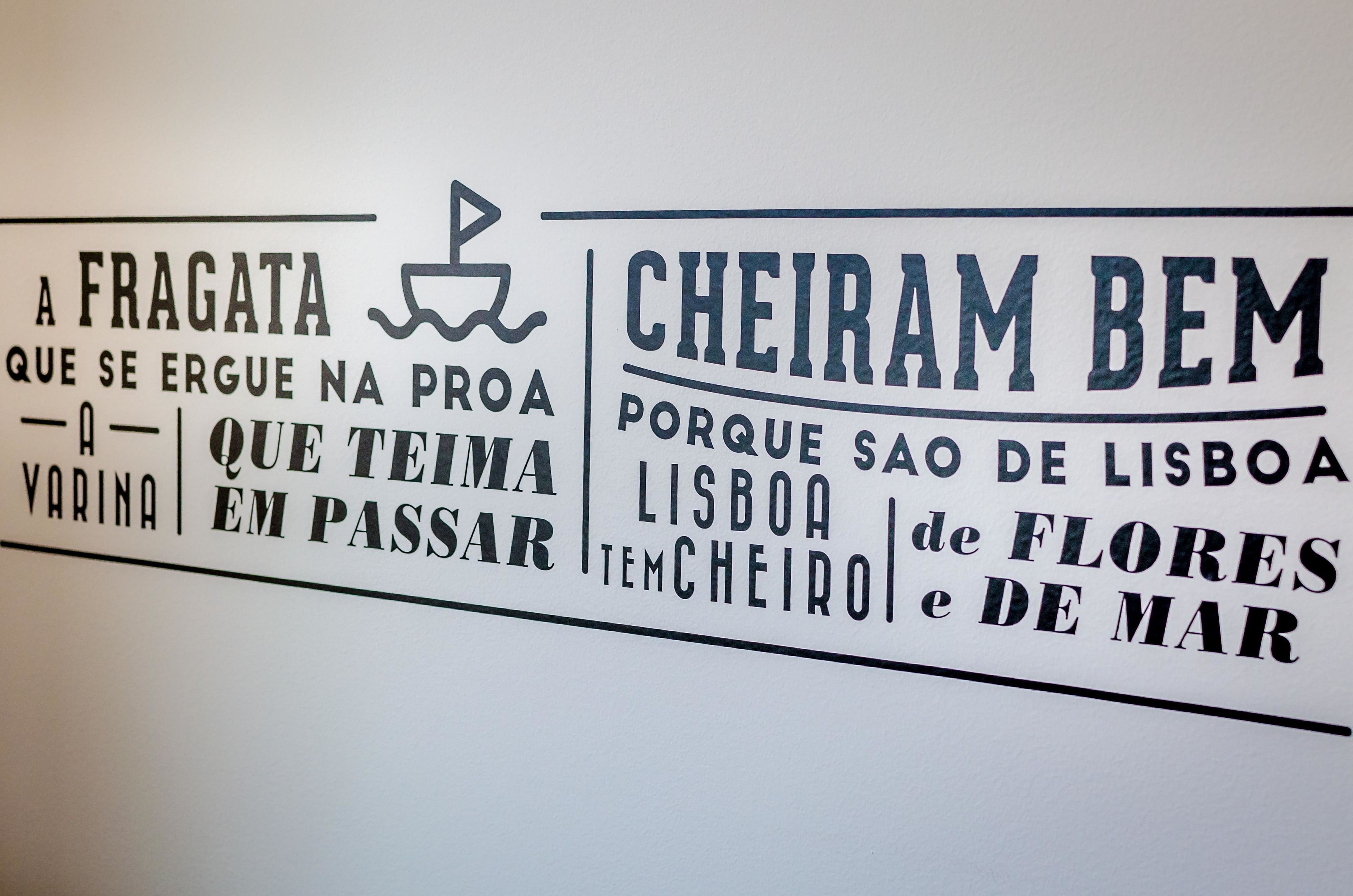 A wall with text in Portuguese, including phrases like "A FRAGATA" and "CHEIRAM BEM."