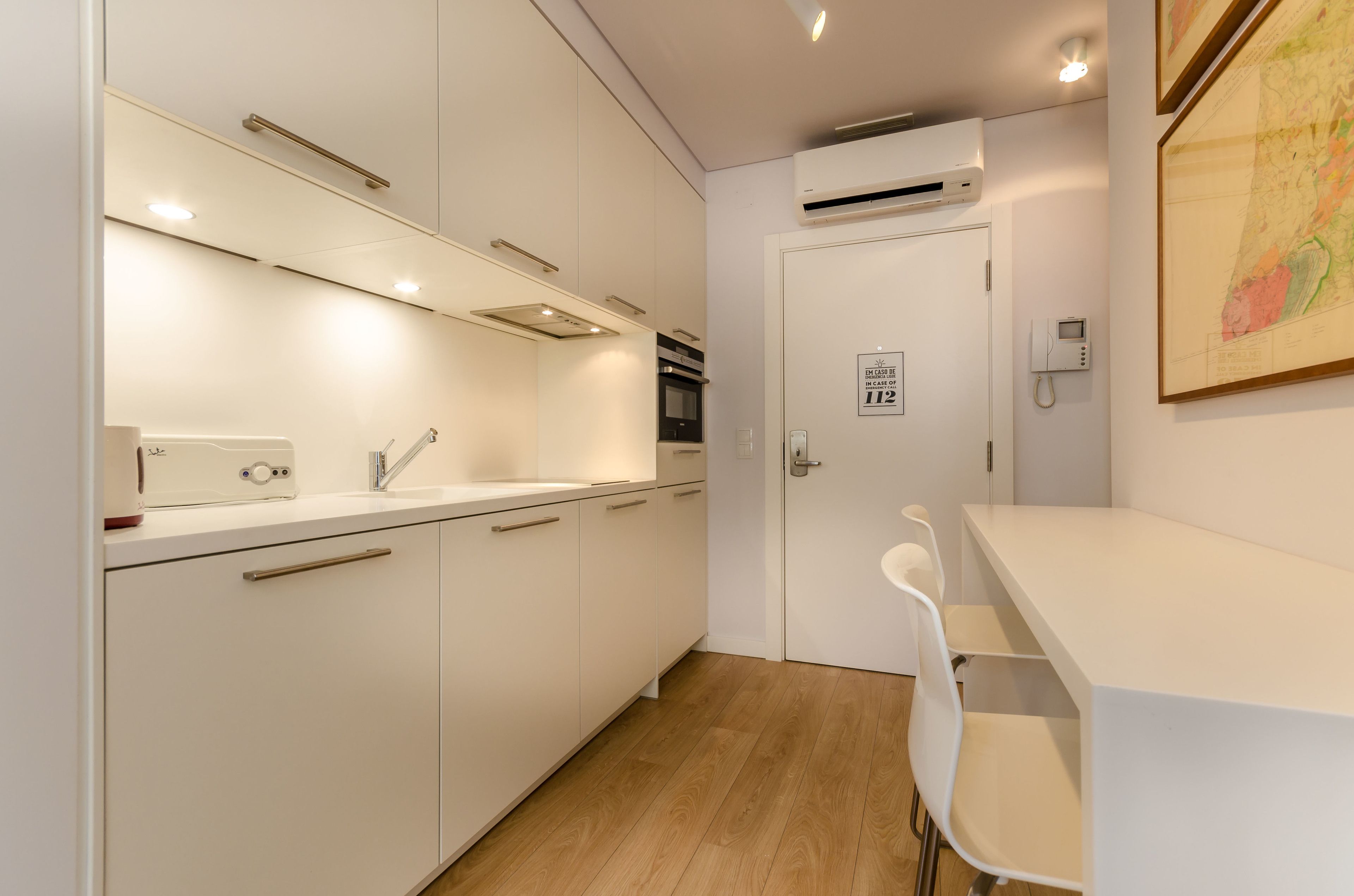 Una cocina moderna con armarios blancos, horno empotrado y encimera blanca.