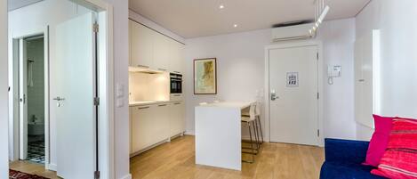 A modern apartment with a kitchen, a dining area, and a living room with a blue sofa.
