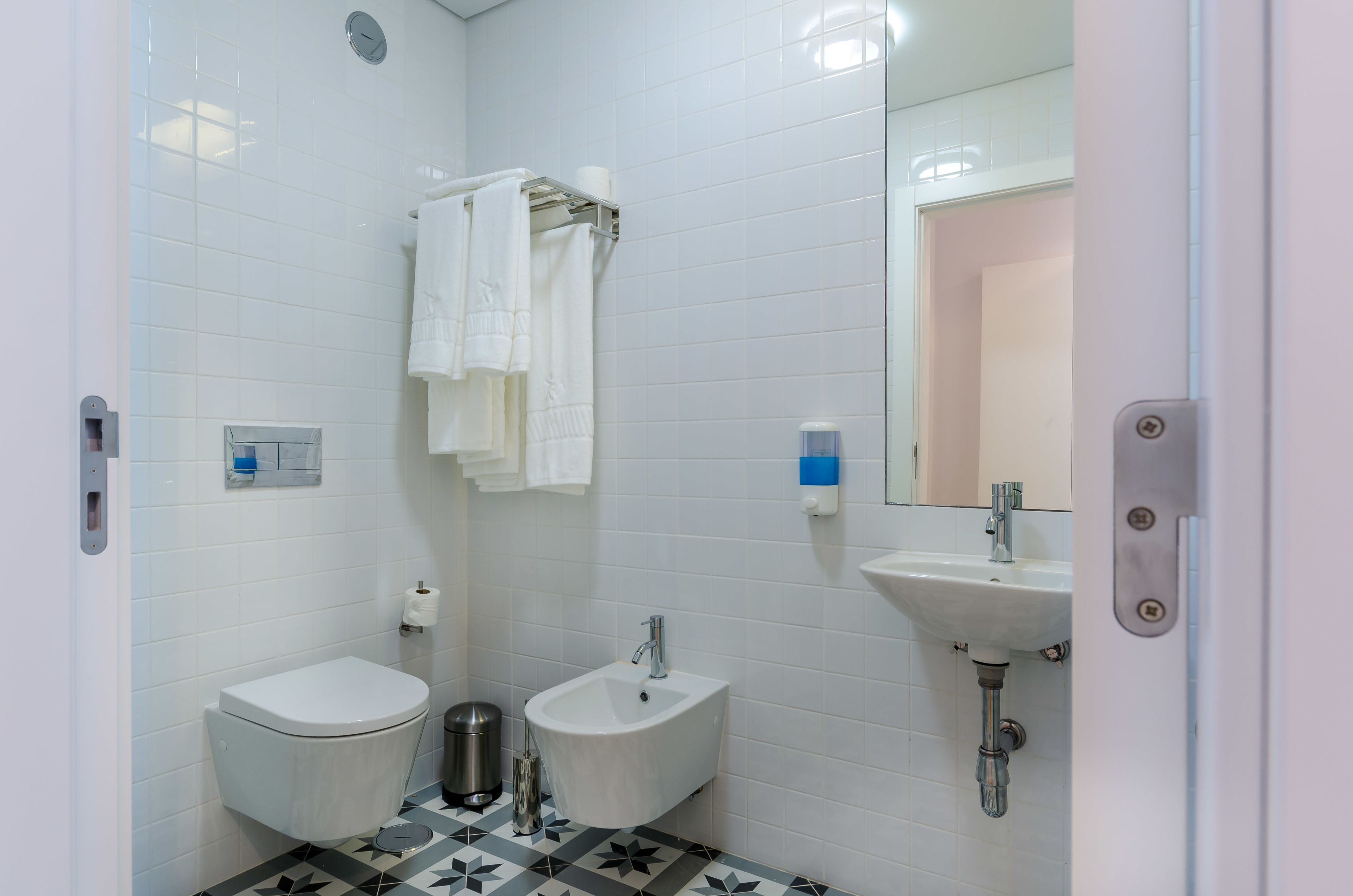 Een badkamer met toilet, bidet, wastafel en spiegel.