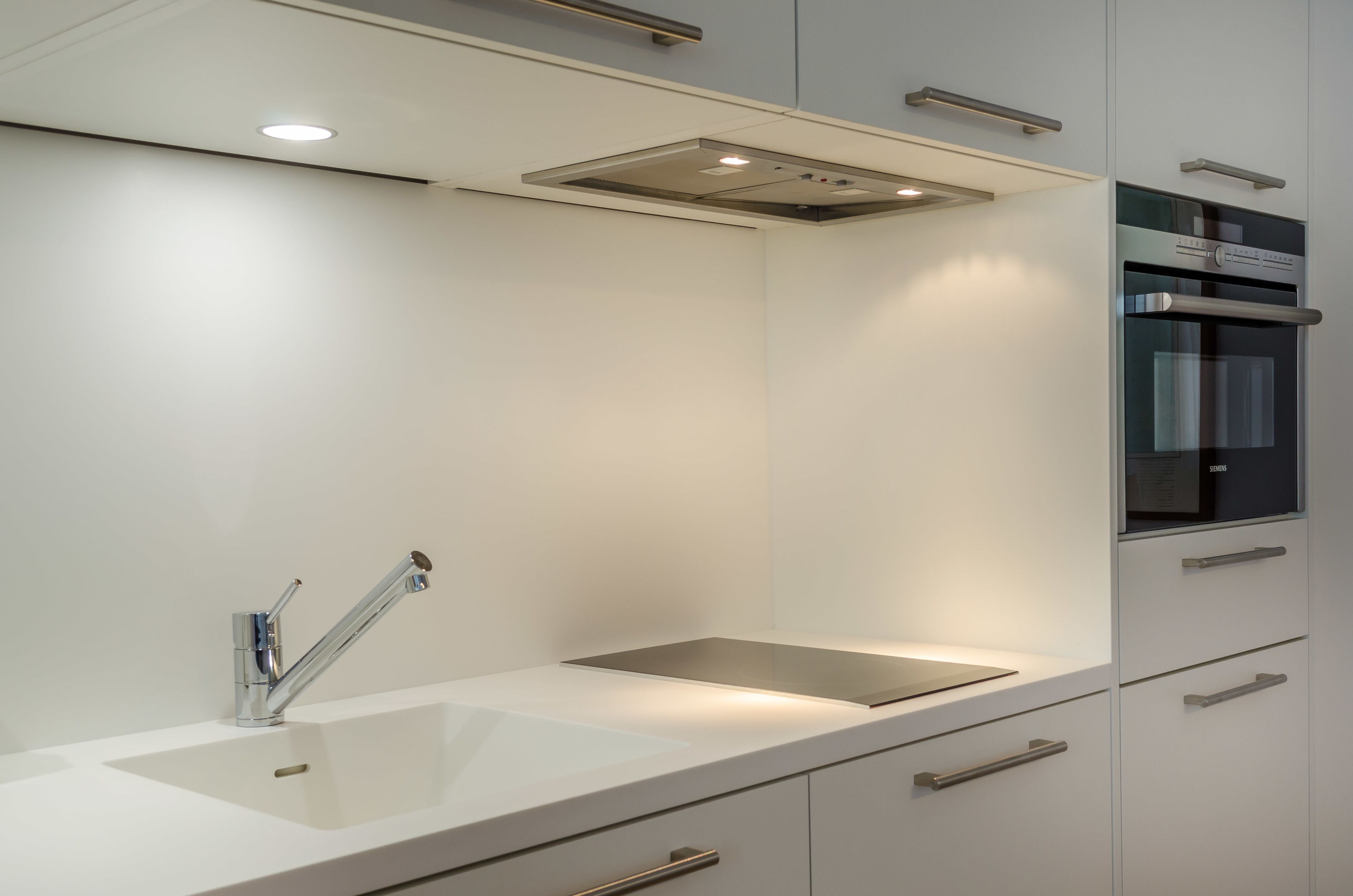 A modern kitchen with a stainless steel sink, a built-in oven, and a sleek countertop.