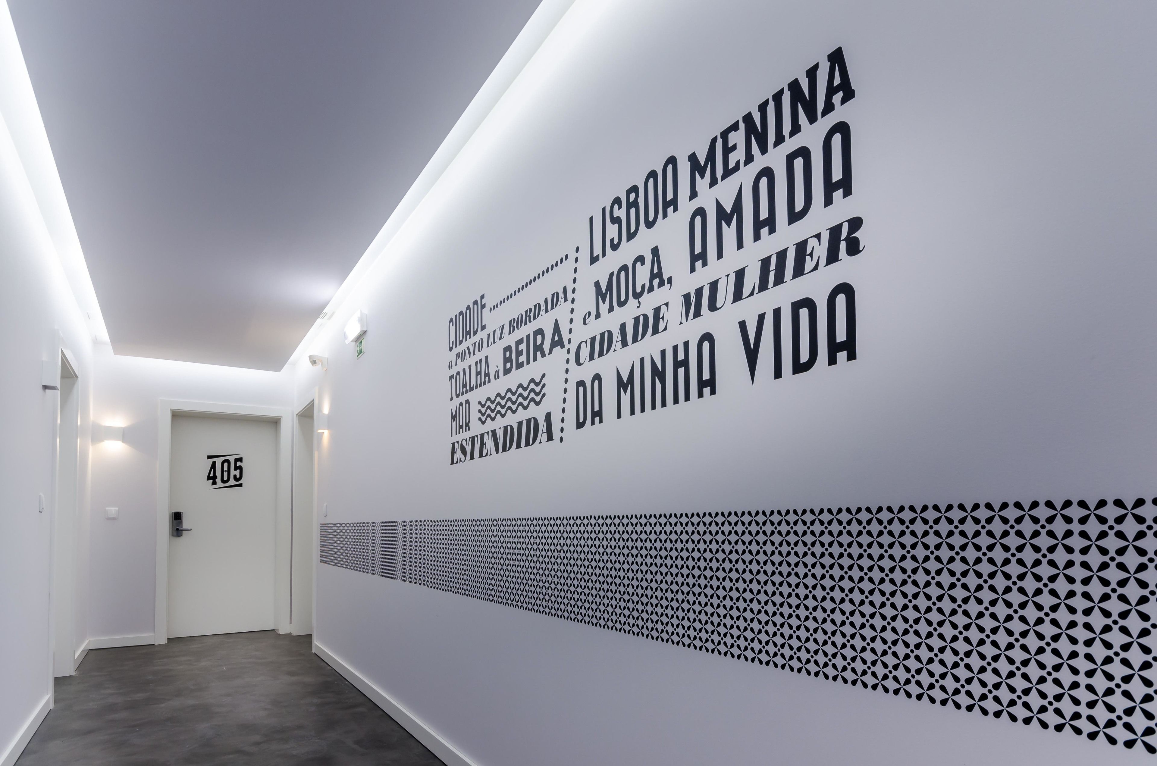 A hallway with a white wall featuring text and a geometric pattern.