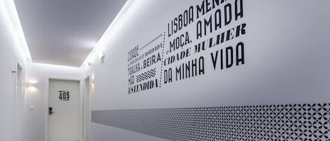 A hallway with a white wall featuring text and a geometric pattern.