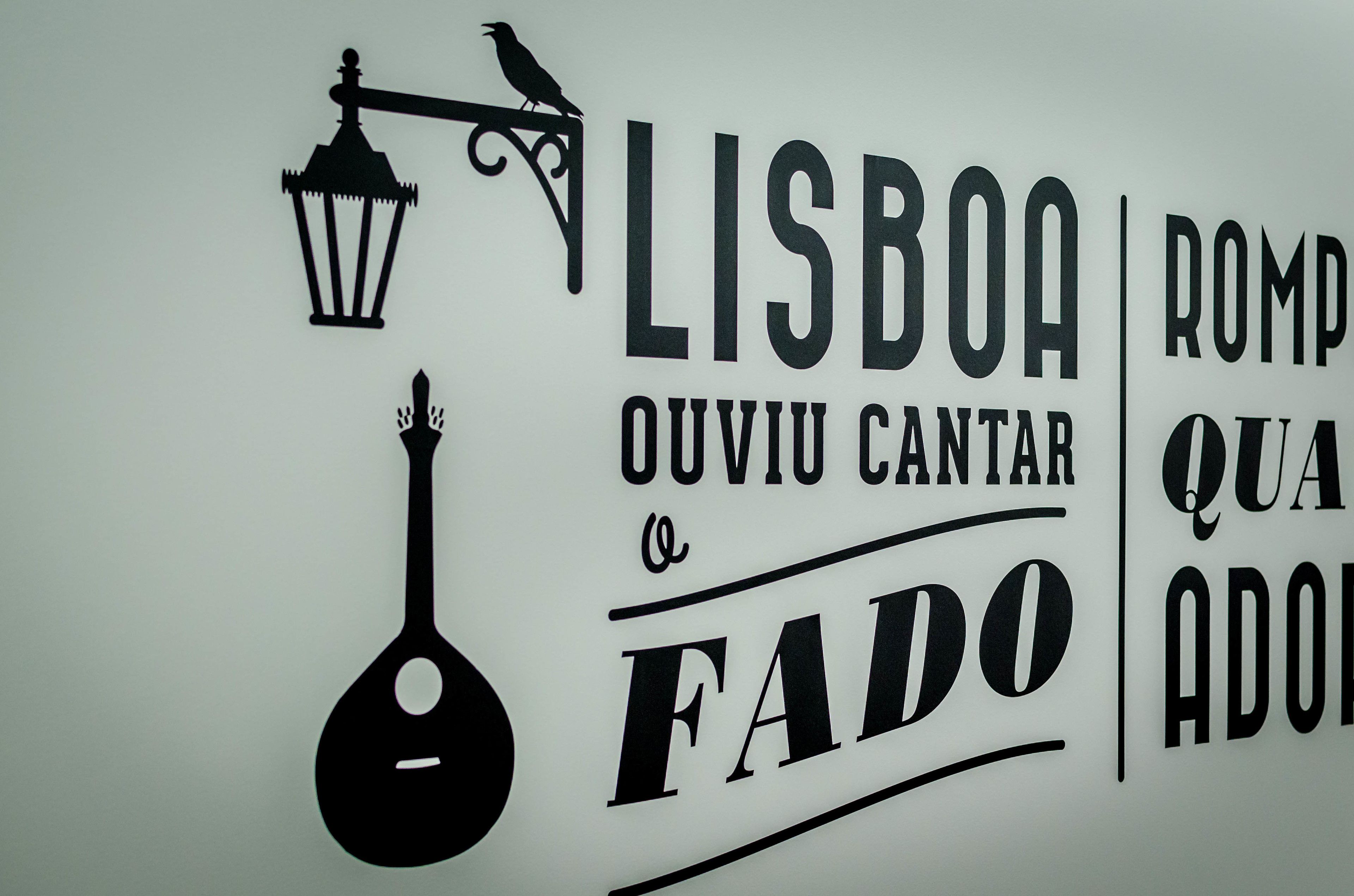 A wall with text and a silhouette of a street lamp and a bird.