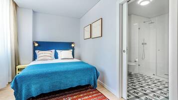 A bedroom with a bed, a shower, and a patterned rug.
